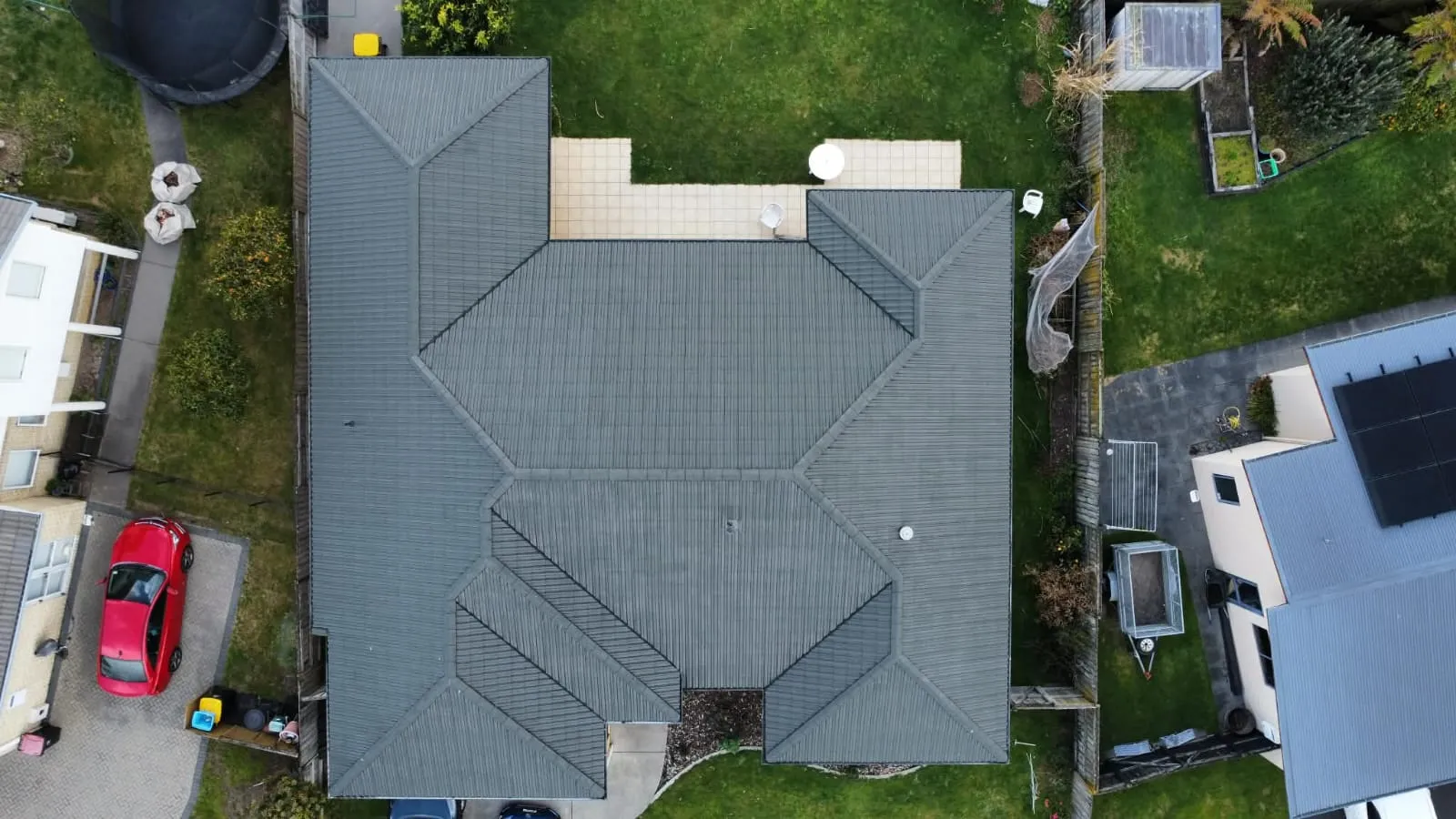 Overhead drone shot of a large hipped tile roof coated in slate grey, every ridge and valley evenly covered